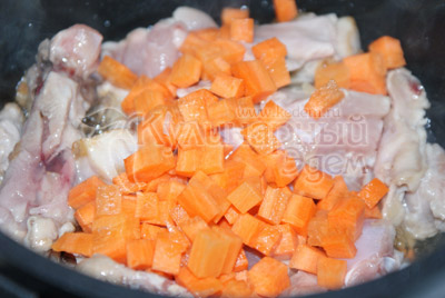 Добавить в лук кусочки курицы, резанные шампиньоны и кубиками нарезанную морковь. 