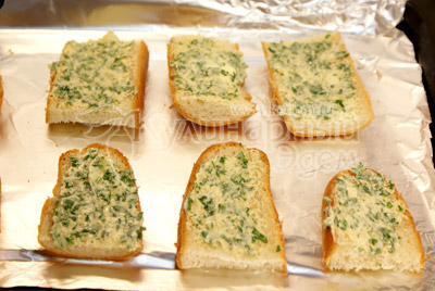 Намажьте кусочки булочки смесью масла с зеленью и специями и выложите кусочки на противень