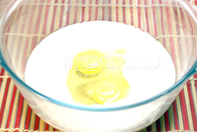 Отдельно в большой миске смешать кефир, яйца (оставить 1 желток) и растительное масло