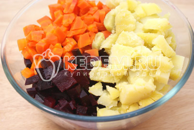 Свеклу, морковь и картофель заранее отварить, остудить и очистить. Смешать в миске кубиками нарезанные свеклу, картофель и морковь