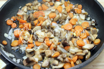 На 2 ст. ложках растительного масла обжарить половину мелко нашинкованного лука, кружочками нарезанную морковь и ломтиками нарезанные грибы. Обжаривать 2-3 минуты. 
