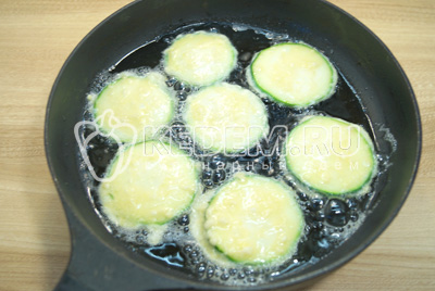 Окунать колечки кабачка в кляр и обжарить на сковороде с двух сторон до золотистой корочки на растительном масле.