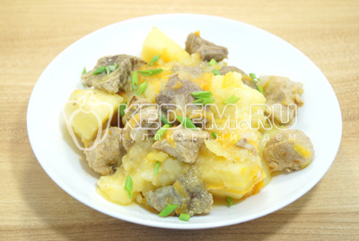 Тушеный картофель с мясом выложить на тарелки и поспать мелко нашинкованным зеленым луком.