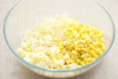Добавить в миску кубиками нарезанные ананасы, 100 грамм кубиками нарезанного сыра и 100 грамм консервированной кукурузы.