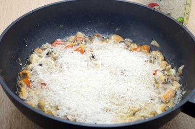 Высыпать длиннозерный рис и разровнять, прикрыть крышкой и готовить на медленном огне 15-20 минут.
