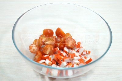 В миску нарезать кубиком 100 грамм крабовых палочек и половинками помидоры черри.