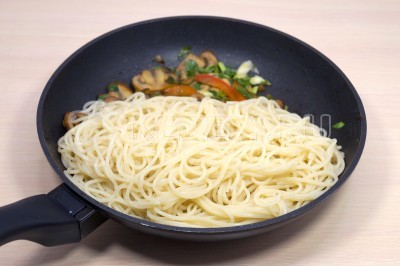 Добавить спагетти в сковороду к грибам и перемешать.