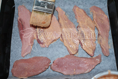 Мясо разрезать на небольшие ломтики шириной 2 см и слегка отбить. Мясо посолить и поперчить. Обмазать каждый ломтик с двух сторон томатным соусом и выложить на противень. 