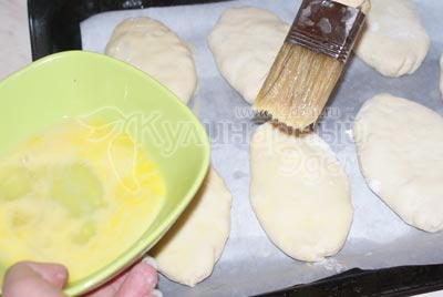 Выложить пироги на противень застеленный пергаментом и обмазать яичным желтком