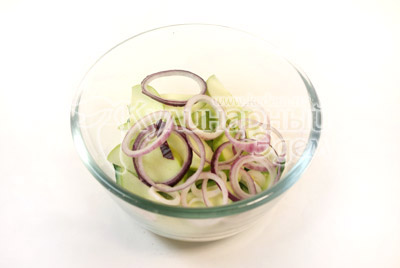 В миске приготовьте салат. Огурцы нарежьте тонкими кружками, ломтиками зелёное яблоко, кольцами лук