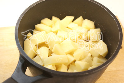 В глубокую кастрюлю выложить картофель нарезанный кубиками