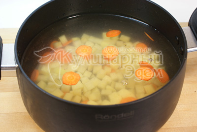 Для приготовления супа с куриными тефтелями воду или готовый куриный бульон вскипятить. Картофель нарезать кубиками, морковь кружочками. Добавить в кастрюлю. Варить до полуготовности