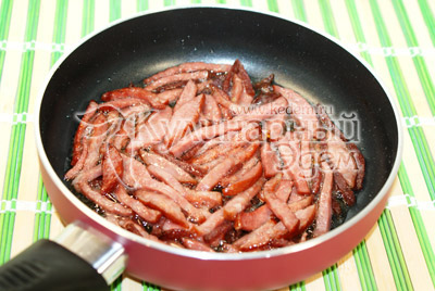 На сковороде обжарить нарезанный соломкой колбасу и салями