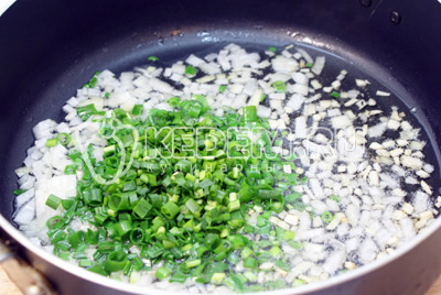 Добавить мелко порезанный зеленый лук и обжаривать 1-2 минуты