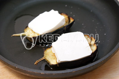 На готовые половинки баклажана выложить ломтики сыра