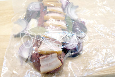 Мясо аккуратно переложить в пакет для запекания ТМ «Paclan». Кусочки лука и лавровый лист уложить по бокам. 