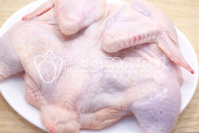 Курицу разрезать по грудинке и развернуть. Накрыть пищевой пленкой и немного отбить