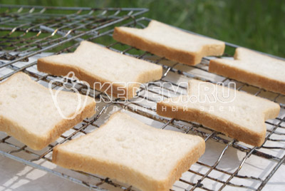 На решетку выложить ломтики хлеба, и сбрызнуть их растительным маслом