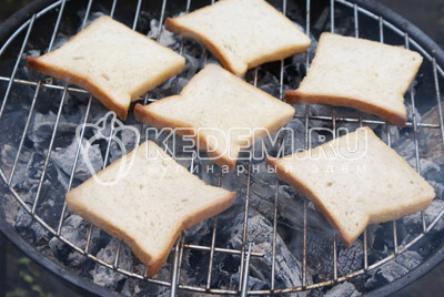Выложить ломтики хлеба на решетку и жарить на углях, буквально по 1 минуте с каждой стороны