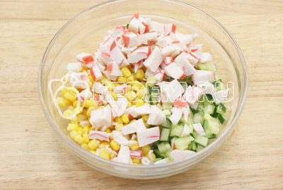 Чтобы приготовить салат с крабовыми палочками и огурцом, в миске нужно смешать мелкими кубиками нарезанный свежий огурец, крабовые палочки и кукурузу.
