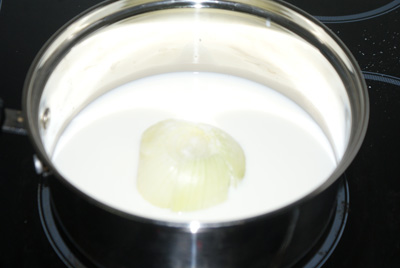 В небольшую кастрюлю или сотейник сложить луковицу, залить молоком и довести до кипения. Накрыть крышкой и дать настоятся 20 минут. Процедить