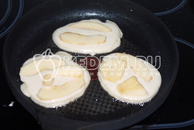 На хорошо разогреть сковородку с растительным маслом выкладываем ложкой тесто в форме оладий, сверху выкладываем несколько яблочных долек. Жарим до румяных корочек с двух сторон
