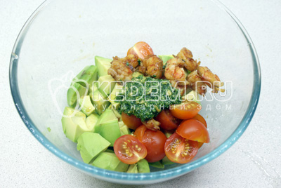 В миску сложить нарезанный крупным кубиком авокадо, разрезанные пополам помидорки черри, креветки и соус песто