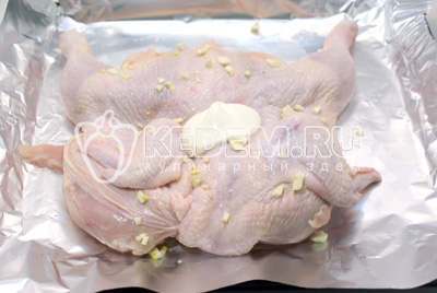 Выложить курицу на противень с фольгой и хорошо натереть солью и рубленным чесноком. Немного обмазать майонезом
