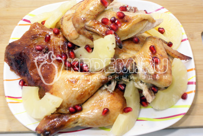 Готовую курицу остудить и разделить на порционные кусочки. Выложить на блюдо с ломтиками ананаса, зеленью и зернами граната. 