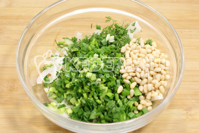 Добавить в миску с салатом мелко нашинкованный зеленый лук, зелень укропа и кедровые орехи