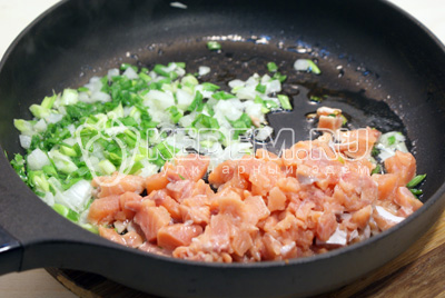 Обжарить на сковороде с растительным маслом рыбу, репчатый и зеленый лук, 2-3 минуты