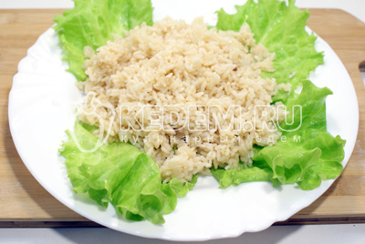 Готовый рис выложить на блюдо с листьями салата