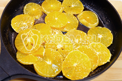 Выложить ломтики апельсинов и обжаривать на среднем огне 1-2 минуты
