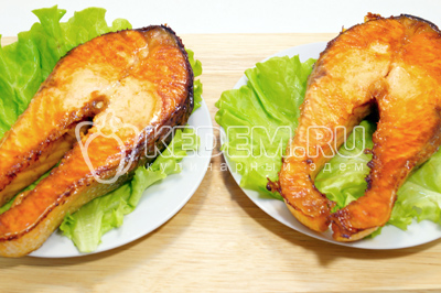 Готовые стейки немного остудить и выложить на тарелки с листьями салата, зеленью и помидорчиками черри