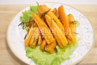 Запеченную морковь немного остудить. Выложить на блюдо с листьями салата
