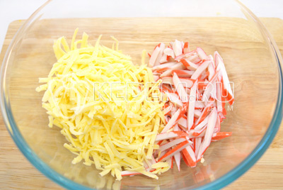 В миску нарезать соломкой палочки и натереть на крупной терке сыр.