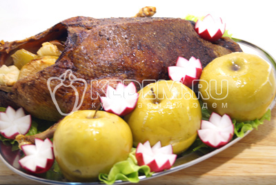 Готовую запеченную утку выложить на блюдо с яблоками, листьями салата, ягодами клюквы и овощами.