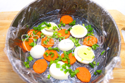 Выложить на дно формы кружочками нарезанную морковь и отварное яйцо, зелень.