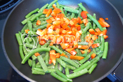 На сковороде с растительным маслом обжарить фасоль и кубиками нарезанный перец 2-3 минуты.