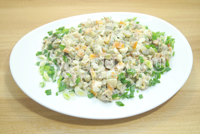 Выложить салат на блюдо и украсить зеленым луком.