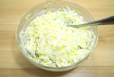 Добавить в миску тертые яйца и хорошо перемешать.