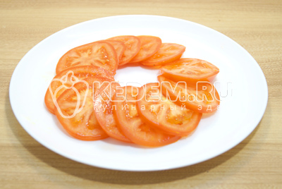 Нарезать тонкими ломтиками помидоры и выложить на блюдо.