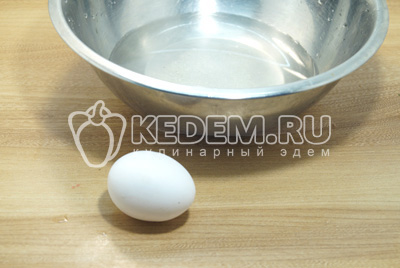 Для приготовления теста в миску налейте холодную воду и разбейте яйцо.