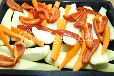 Разрезать морковки на части и выложить к кабачкам. Добавить ломтиками нарезанные перцы.