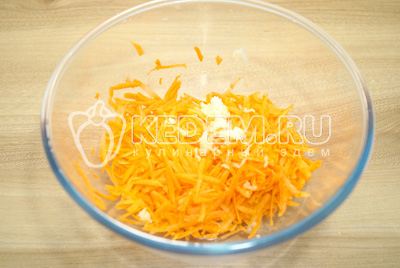 В миску с тертой морковью добавить прессованный чеснок.