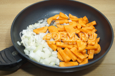 На сковороде разогреть оливковое масло и выложить кубиками нарезанный репчатый лук и крупно нарезанную морковь.