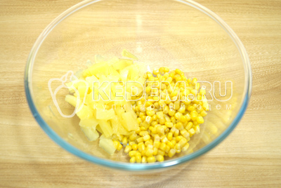 В миску выложить кукурузу и кубиками нарезанные ананасы.