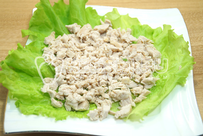 На блюдо выложить салатные листья и слоем выложить половину мелко нарезанного куриного филе. Смазать майонезом.