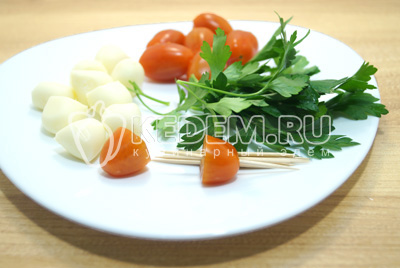 Шарики сыра и помидоры нарезать на половинки. На низать на шпажки половинку помидорки.