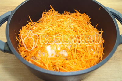 Добавить тертую морковь. Тушить курицу с морковью 3-5 минут.